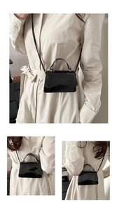 Detailed view of black glossy patent leather mini crossbody bag with top handle and flap