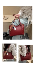 Close-up of red leather tote bag with white stitching and decorative silk scarf handle