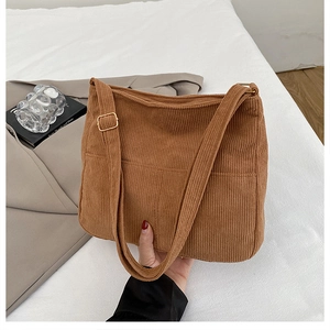 Détail du sac fourre-tout en velours côtelé marron avec poche avant et boucle dorée