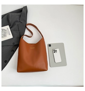 Flat lay of caramel brown tote bag with FASHION lettering and lifestyle accessories