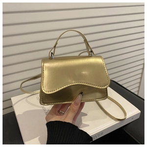 Macro shot of gold mini crossbody bag with wavy flap and metallic top handle design