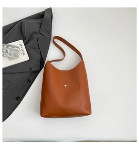 Detail view of a brown faux leather tote bag with a front pocket and silver metal buckle