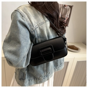Side view of black matte underarm bag with oversized leather-wrapped buckle on model