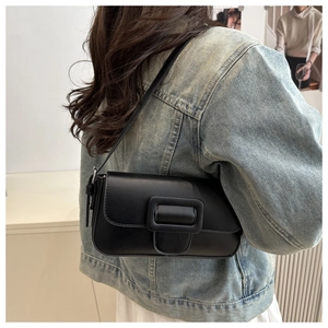 Side view of model wearing a minimalist black leather flap shoulder bag with buckle