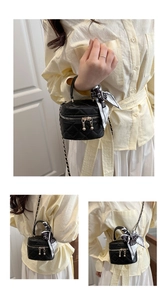 Detail of mini black quilted bucket bag with silk scarf handle and chain strap for girls