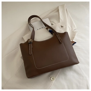 Detail of dark brown leather tote bag with white contrast stitching and floral silk scarf