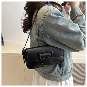 Detail view of a black matte faux leather baguette bag with a stylish square buckle strap