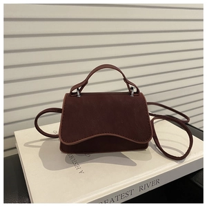 Close-up of wine red matte crossbody bag featuring wave-edge flap and silver hardware