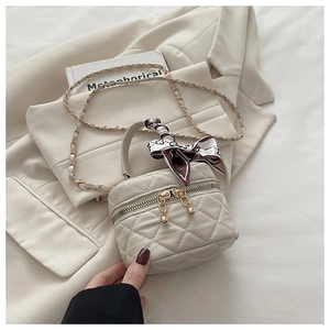 Detail of a mini quilted bucket bag with a decorative silk scarf on the handle