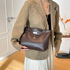 Dark brown woven bucket bag with elegant gold chain strap and animal charm for women