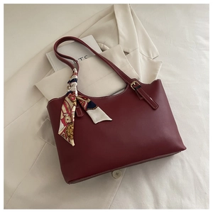 Detail of burgundy tote bag featuring a decorative silk scarf and gold buckle hardware