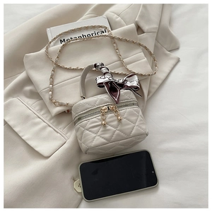 Mini cream quilted bucket bag with silk scarf handle and metal chain for scale reference