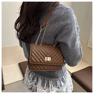 Brown chevron quilted leather crossbody bag with gold chain strap on a model shoulder