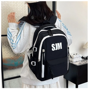 Rear view of black and white color-block large capacity backpack worn by a model