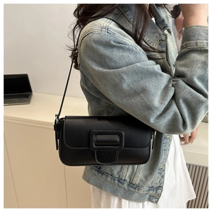 Close-up of minimalist black matte leather baguette bag with oversized buckle detail
