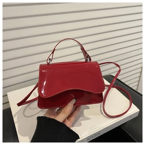 Detail of red patent leather mini bag featuring wavy flap edge and glossy texture finish