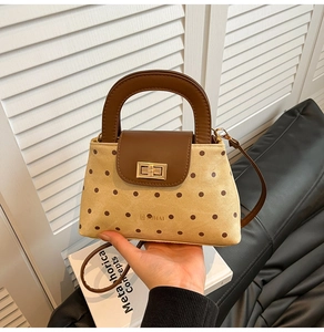 Détail d'un petit sac à main à pois avec finitions en cuir marron et fermoir doré