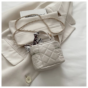 Close-up of beige quilted mini bucket bag with silk scarf handle and golden chain
