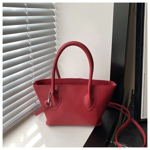 Detail of red lychee textured bucket bag with silver hardware and adjustable strap
