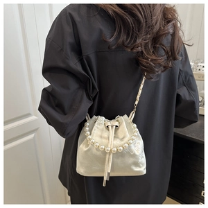 Close-up of floral embroidery on ivory satin bucket bag with pearl handle and chain strap