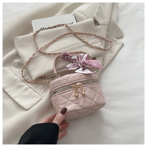 Detailed macro of kids mini bucket bag with pink silk scarf handle and golden chain strap