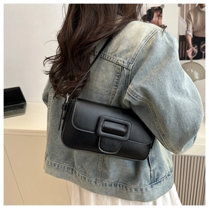 Detailed side view of a black leather underarm bag with a large square buckle flap