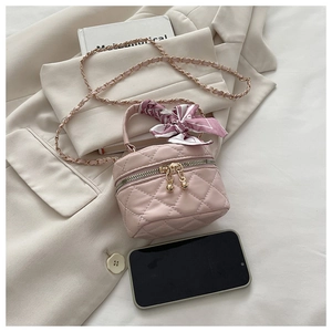 Detailed macro view of a mini pink quilted bag with a silk scarf handle and chain strap