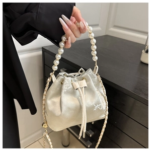 Detail of floral embroidery on ivory satin bucket bag with elegant pearl handle strap
