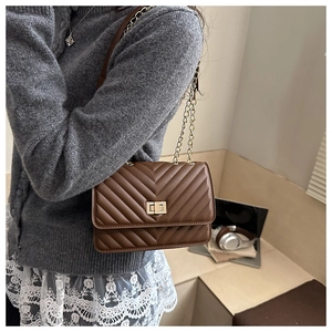 Brown quilted crossbody bag with gold turn-lock and chain strap on a female model