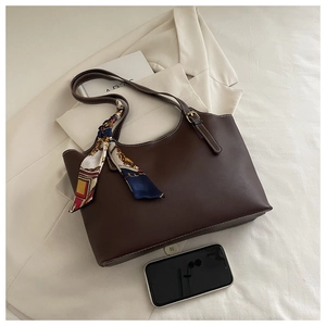 Detail of dark brown leather tote bag with printed silk scarf handle and smooth texture