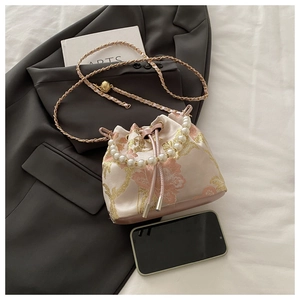 Detail of pink satin bucket bag with gold embroidery and large pearl handle