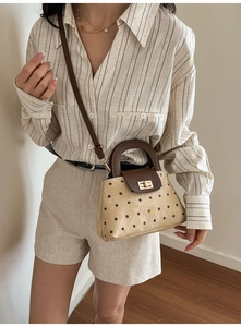 Close-up detail of retro polka dot crossbody bag with leather handle and gold twist lock