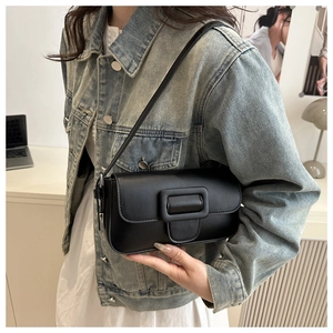 Detail shot of a matte black leather shoulder bag styled with a casual denim outfit