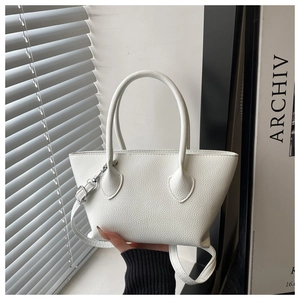 Close-up of white lychee textured leather bucket bag with silver buckle and crossbody strap