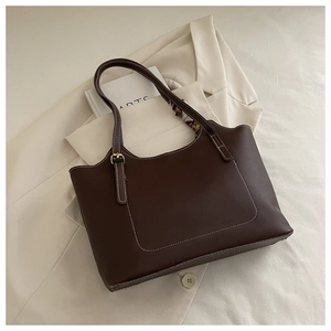 Detail of dark brown leather tote featuring white contrast stitching and golden hardware buckle