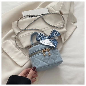 Close-up of light blue quilted mini bucket bag with silk scarf handle and gold chain