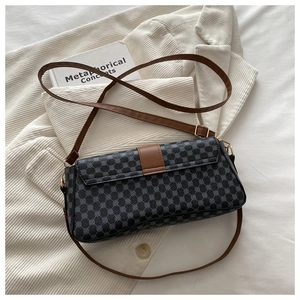 Detail of gray patterned crossbody bag with brown leather straps on white clothing