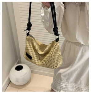 Detail of hand-woven straw bag with black cord shoulder strap and silver metal ring buckle