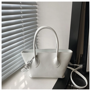 Close-up of white pebbled leather bucket bag texture with silver hardware and shoulder strap