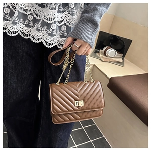 Detailed view of brown chevron quilted bag with gold twist-lock and chain strap