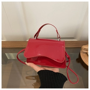 Detail of red patent leather mini handbag with glossy finish and detachable shoulder strap
