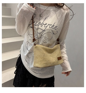 Detail of beige woven crossbody bag featuring leather strap and stylish knot design