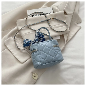 Detail of light blue quilted bucket bag with floral silk scarf and metal chain strap