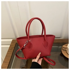 Detail of red pebbled leather bucket bag with dual handles and adjustable shoulder strap