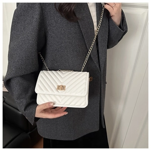 Close-up of a white V-quilted crossbody bag with a gold square lock and chain strap