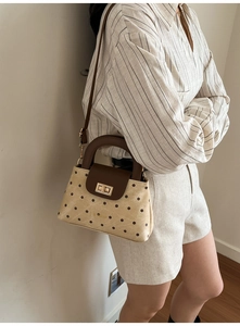 Vue détaillée du sac à main vintage à pois avec fermoir rotatif doré et poignée en cuir
