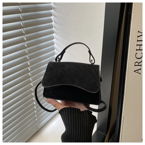 Detailed view of black matte mini handbag with rounded handle and slim strap for women
