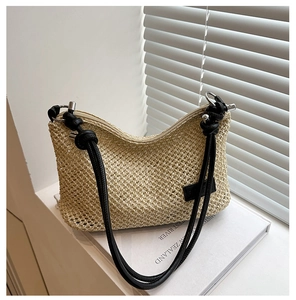 Detail of beige woven straw shoulder bag featuring black rope straps and silver hardware