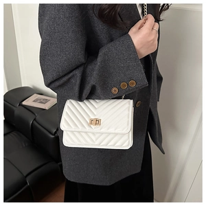 Detail of white quilted crossbody bag with V-shaped stitching and golden twist lock
