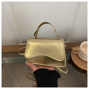 Detailed shot of a gold metallic faux leather mini bag with decorative wavy flap design